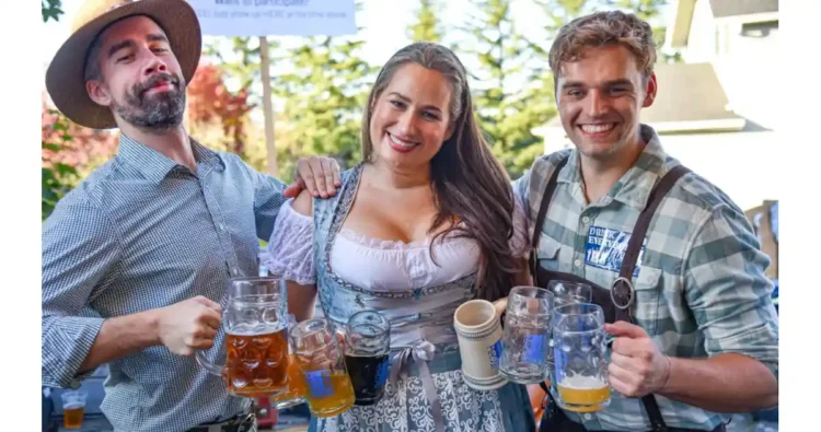 This Weekend, Join Ounces Taproom for Three Days of Oktoberfest Fun Three people in Oktoberfest garb with mugs of beer
