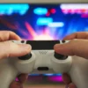 Why Some Games Stay Popular For Decades While Others Disappear Person playing a video game with a controller in front of a colorful gaming screen