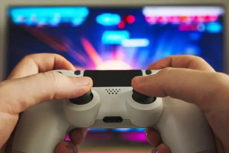 Why Some Games Stay Popular For Decades While Others Disappear Person playing a video game with a controller in front of a colorful gaming screen