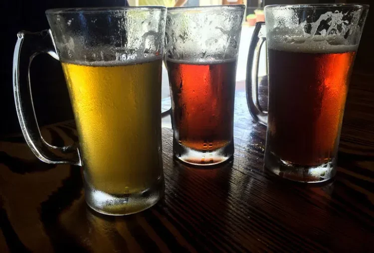 Three beer glasses on a wooden table.