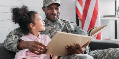 The Four Army Mathematicians Who Worked Out Blackjack Strategy African American male reading a book sitting beside his daughter.