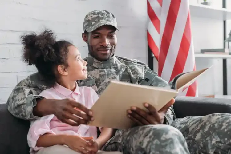 The Four Army Mathematicians Who Worked Out Blackjack Strategy African American male reading a book sitting beside his daughter.