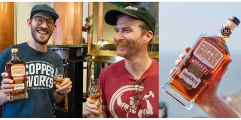 Two men sharing whiskey and hoisting a bottle