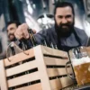 The New Taproom Downtime: What People Do While Waiting for the Next Pour Men selecting craft beer bottles in a brewery taproom with a freshly poured beer on the counter.