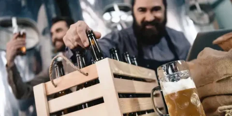 Men selecting craft beer bottles in a brewery taproom with a freshly poured beer on the counter.
