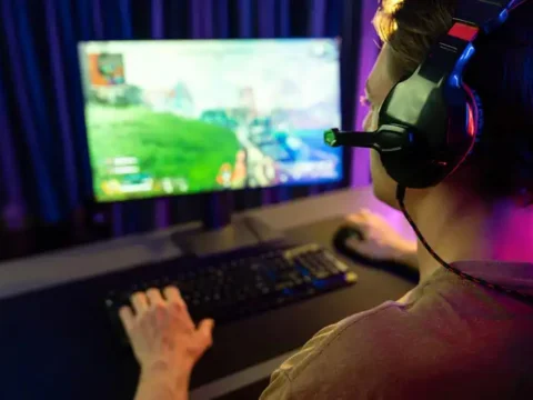 4 Useful Tips for Improving Your Online Gaming Skills Man playing a video game on a PC while improving his online gaming skills.